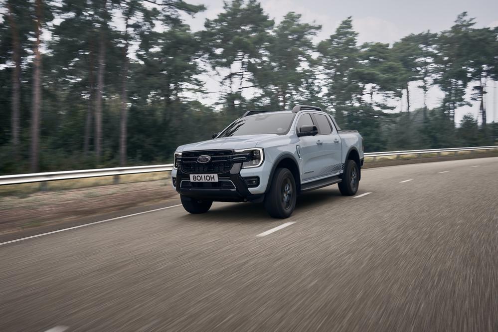 Ford Ranger Plug-In Hybrid driving on a road with forest background.