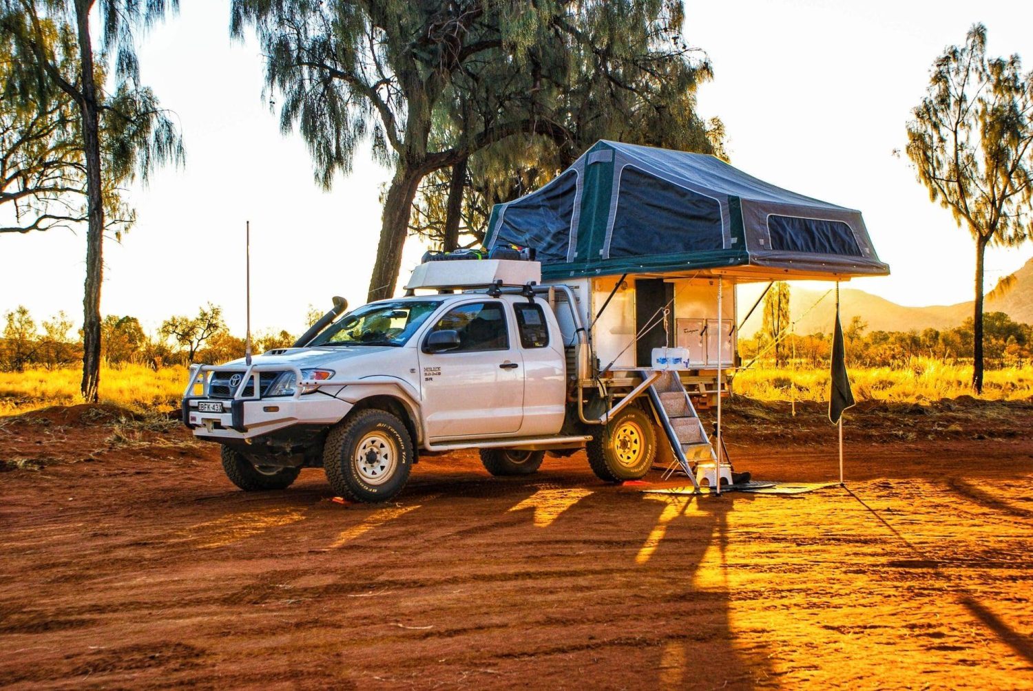 Rugged 4x4 truck with rooftop tent camper parked in scenic wilderness at sunset